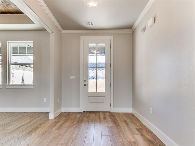 doorway featuring ornamental molding, light wood finished floors, visible vents, and baseboards