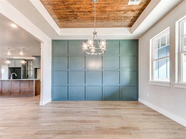 unfurnished dining area with a raised ceiling, wooden ceiling, and a decorative wall