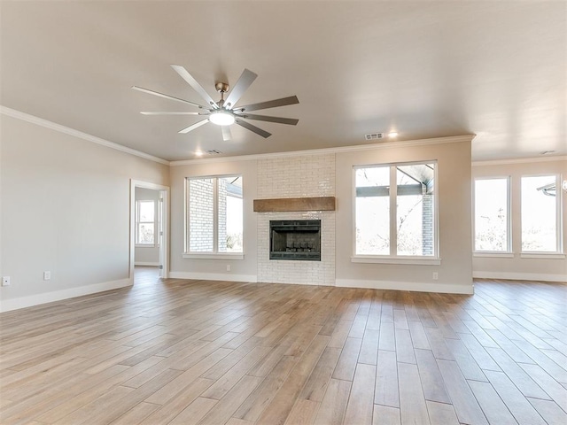 unfurnished living room featuring light wood-style floors, ornamental molding, a brick fireplace, ceiling fan, and baseboards