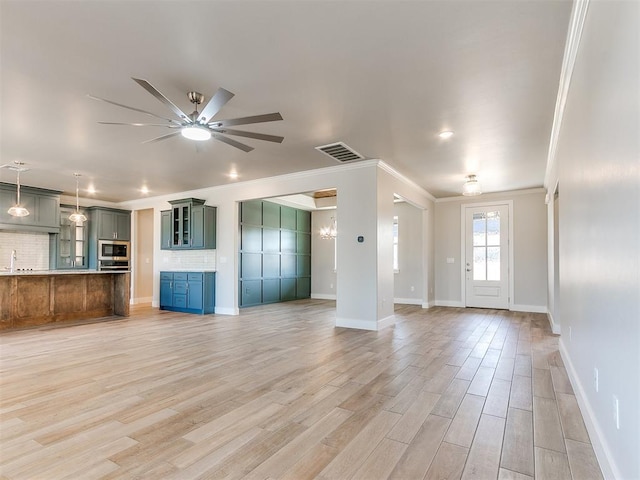 unfurnished living room featuring light wood-style floors, a ceiling fan, visible vents, and crown molding