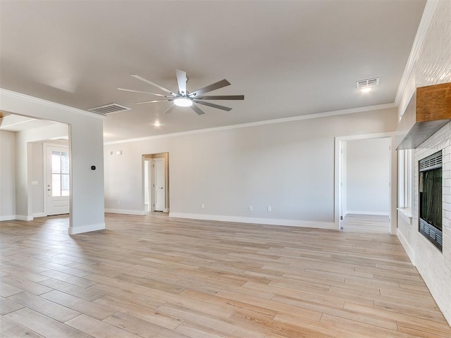 unfurnished living room featuring a fireplace, visible vents, a ceiling fan, light wood finished floors, and crown molding