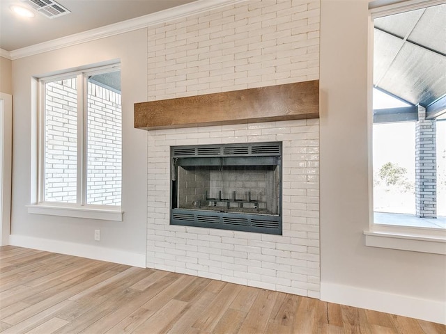 details with wood finished floors, visible vents, baseboards, a brick fireplace, and crown molding