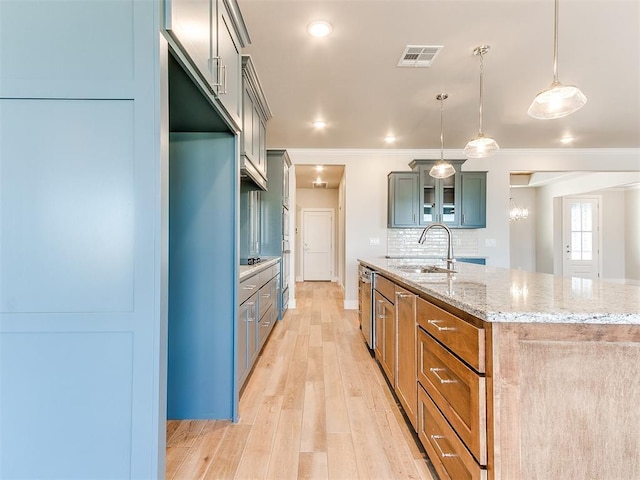 kitchen featuring a center island with sink, light wood finished floors, visible vents, backsplash, and a sink