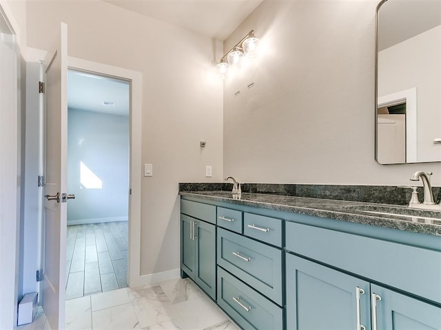 bathroom with double vanity, marble finish floor, baseboards, and a sink