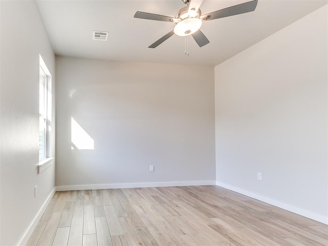 spare room featuring light wood-style floors, visible vents, baseboards, and a ceiling fan