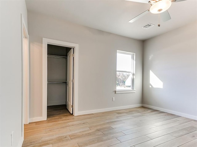 unfurnished bedroom with light wood finished floors, visible vents, a spacious closet, ceiling fan, and baseboards