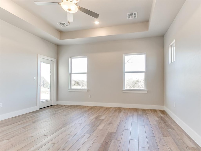 unfurnished room featuring a wealth of natural light, visible vents, light wood-style flooring, and baseboards