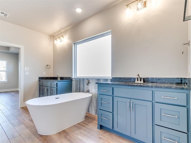 bathroom featuring two vanities, a sink, visible vents, and wood finished floors