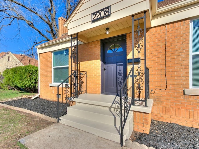 property entrance with brick siding and a chimney