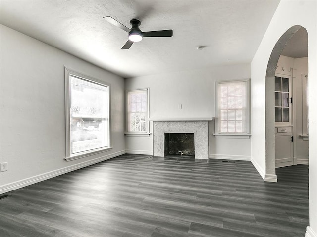 2208 N Hood St, Oklahoma City, OK 73111 - unfurnished living room featuring a ceiling fan, arched walkways, dark wood-style flooring, a high end fireplace, and healthy amount of natural light