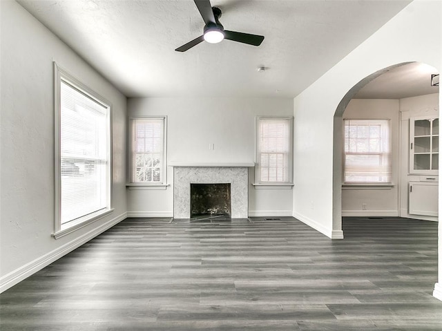2208 N Hood St, Oklahoma City, OK 73111 - unfurnished living room with ceiling fan, wood finished floors, arched walkways, baseboards, and a fireplace