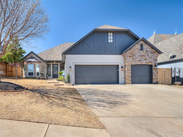 view of front of house featuring roof with shingles, fence, a garage, stone siding, and driveway