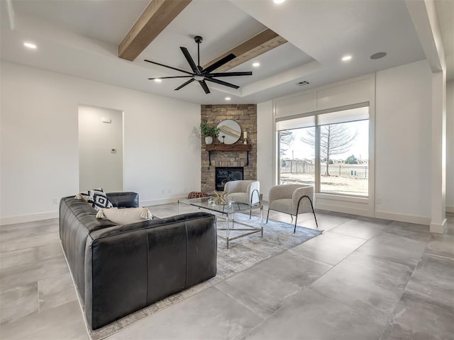 living room featuring baseboards, a stone fireplace, a ceiling fan, and beamed ceiling