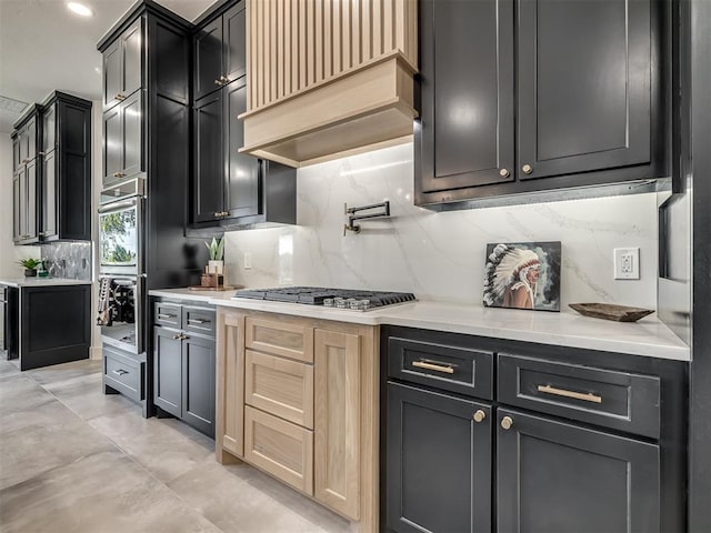 kitchen featuring premium range hood, appliances with stainless steel finishes, light countertops, and decorative backsplash