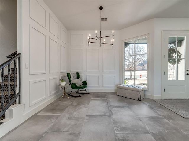 interior space featuring a chandelier, visible vents, and a decorative wall