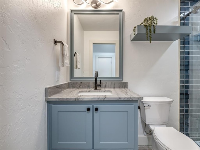 bathroom with toilet, vanity, and a textured wall