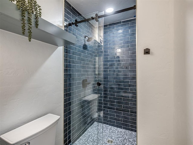 full bathroom with a textured wall, a shower stall, and toilet