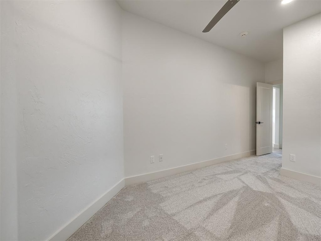 unfurnished room with a ceiling fan, light carpet, and baseboards