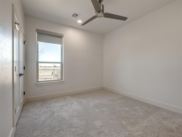 empty room featuring carpet floors, visible vents, baseboards, and a ceiling fan