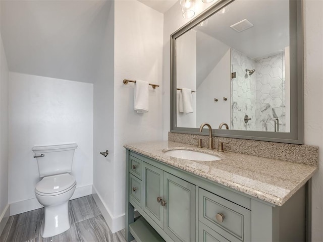 bathroom featuring toilet, visible vents, vanity, baseboards, and walk in shower