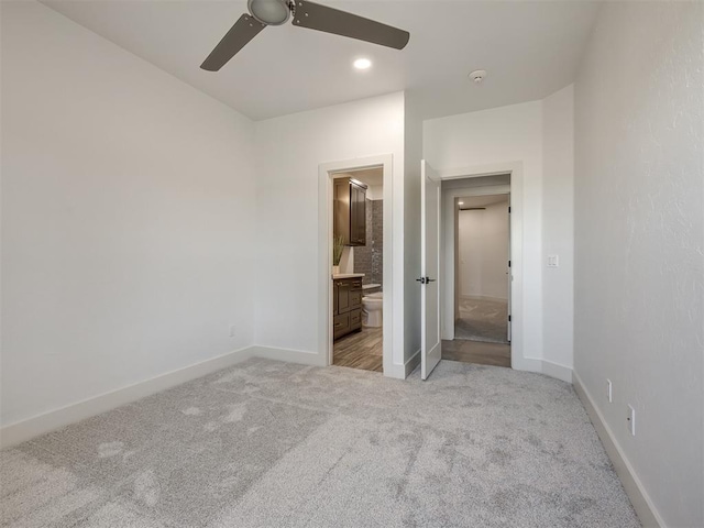 unfurnished bedroom with carpet, connected bathroom, baseboards, and ceiling fan