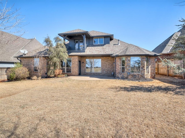 view of front of property featuring a balcony, a patio area, fence, and a front lawn