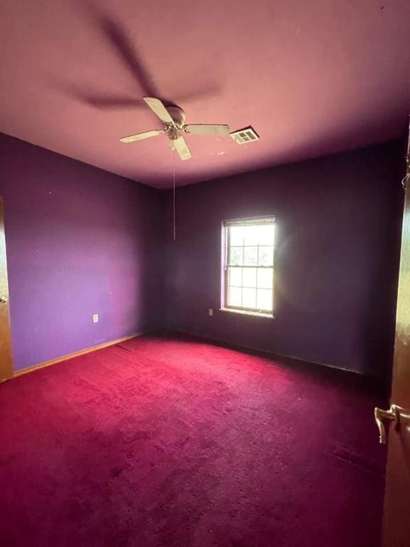 spare room with ceiling fan, visible vents, and carpet flooring