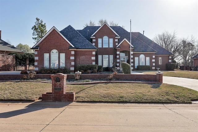 traditional home featuring a shingled roof, a front lawn, and brick siding