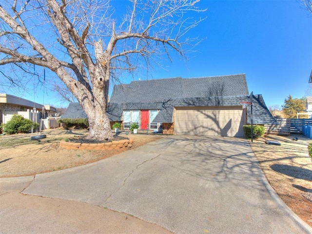 view of front facade featuring driveway, roof with shingles, an attached garage, and fence