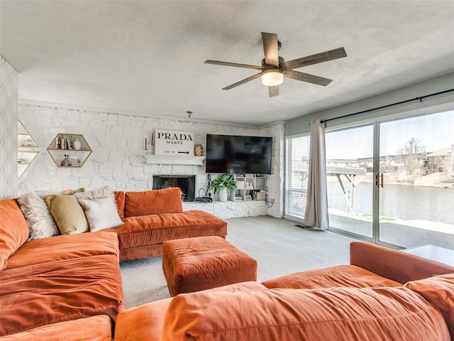 living room with a large fireplace, a textured ceiling, a ceiling fan, and carpet flooring