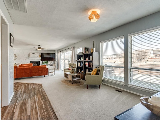 living area with carpet, a textured ceiling, a fireplace, and visible vents