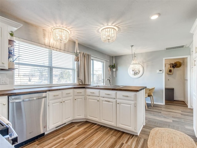 kitchen featuring dishwasher, wooden counters, a sink, and a chandelier