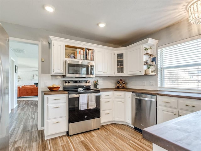 kitchen with open shelves, appliances with stainless steel finishes, light wood-type flooring, and visible vents