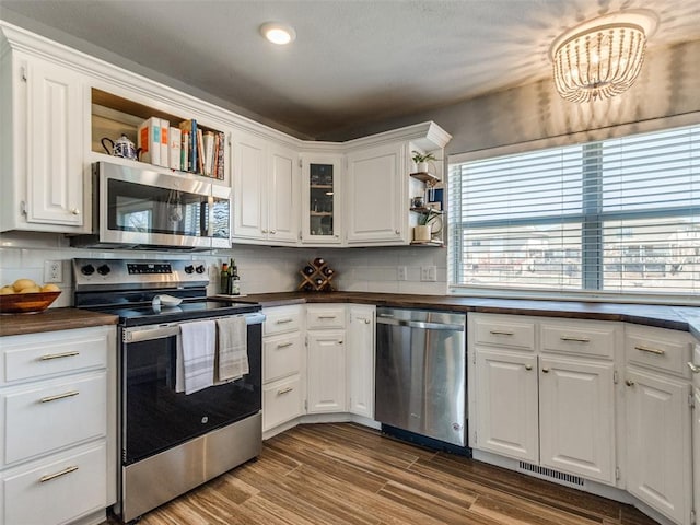 kitchen featuring stainless steel appliances, dark wood-style flooring, white cabinetry, open shelves, and dark countertops