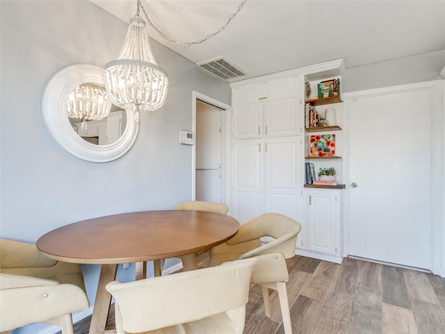 dining space featuring visible vents, light wood-style flooring, and an inviting chandelier