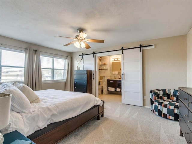 bedroom with light colored carpet, ceiling fan, baseboards, and a barn door