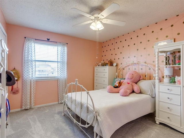 carpeted bedroom with wallpapered walls, baseboards, a ceiling fan, and a textured ceiling