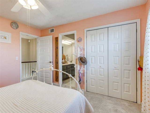 bedroom with light carpet, visible vents, ceiling fan, a textured ceiling, and a closet