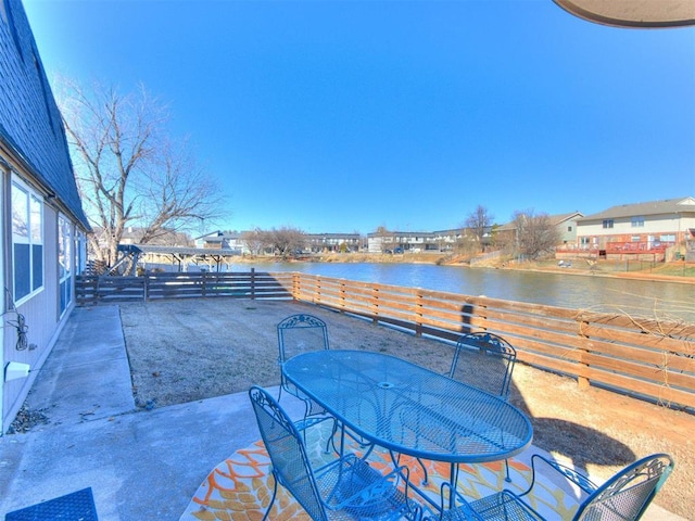 view of patio featuring outdoor dining area, a water view, and fence