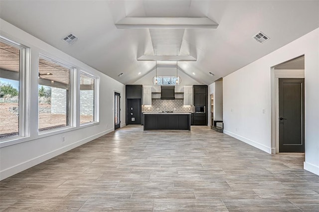 4125 Emery Dr, Edmond, OK 73034 - kitchen featuring open floor plan, backsplash, light countertops, a center island with sink, and lofted ceiling