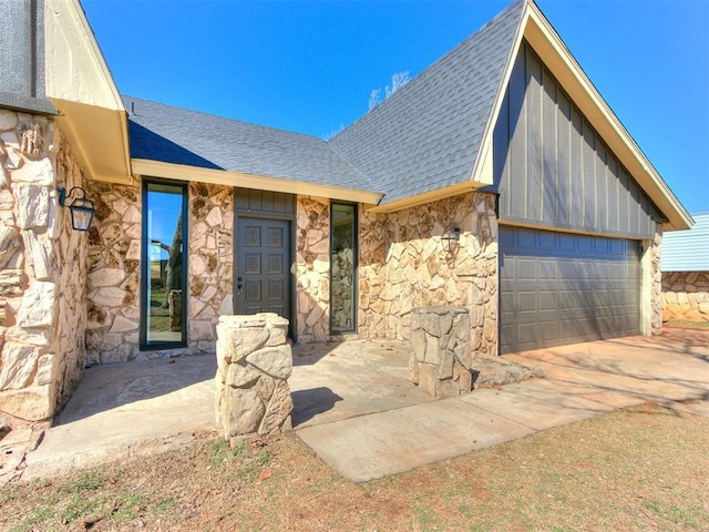 view of front of home with an attached garage, stone siding, board and batten siding, and roof with shingles