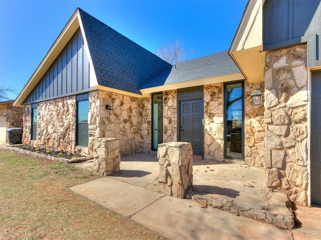 view of front of house with a shingled roof, stone siding, and board and batten siding