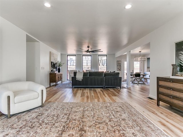 living room featuring light wood-style flooring, baseboards, ceiling fan, and recessed lighting