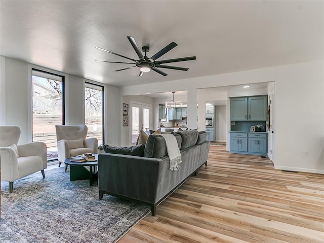 living area with light wood finished floors, ceiling fan, baseboards, and french doors