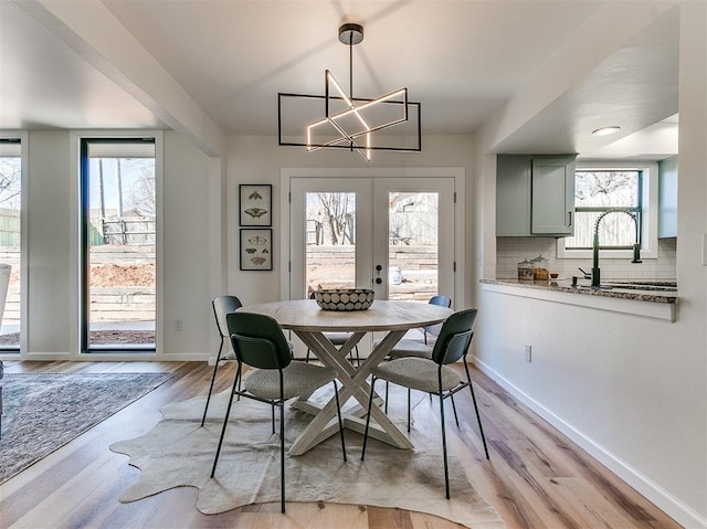 dining space with light wood-type flooring, french doors, and baseboards