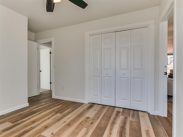 unfurnished bedroom featuring ceiling fan, a closet, light wood-style flooring, and baseboards