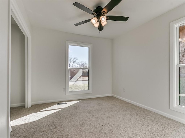 carpeted empty room featuring visible vents, ceiling fan, and baseboards