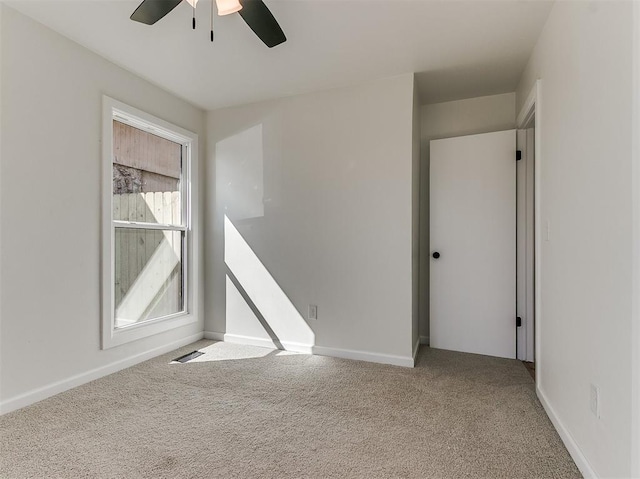 carpeted empty room featuring visible vents, ceiling fan, and baseboards