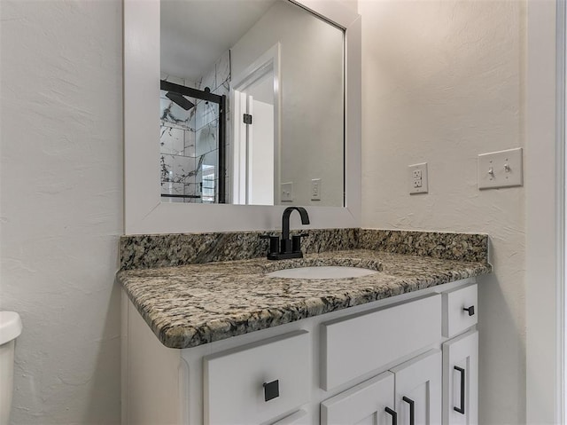 bathroom with a textured wall and vanity