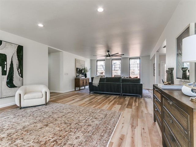 living room with recessed lighting, light wood-type flooring, a ceiling fan, and baseboards